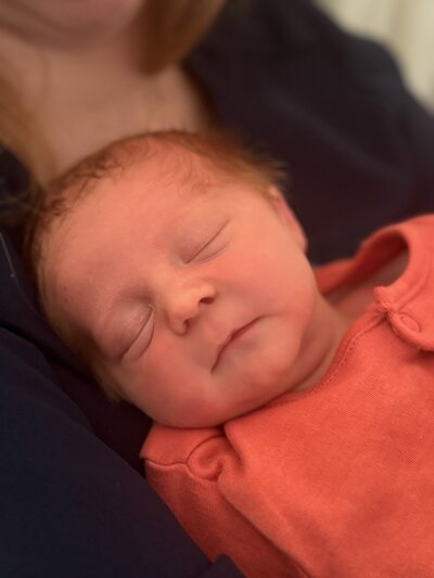 Loïc slaapt, met zijn wangetje tegen de borst van zijn mama.